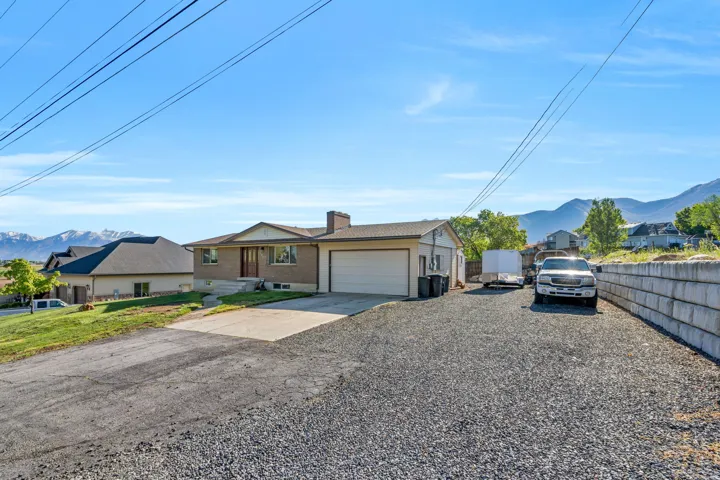 Single story home featuring a mountain view, a residential view, driveway, a chimney, and an attached garage