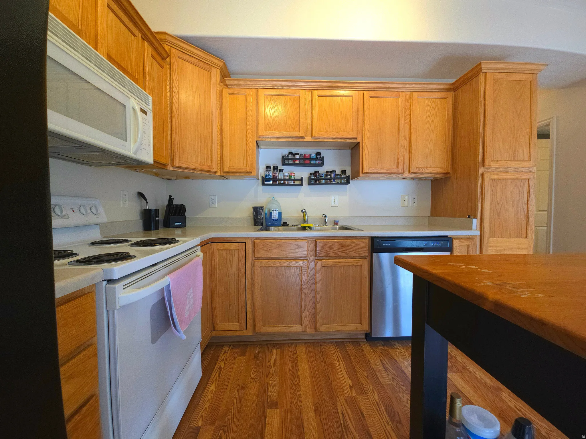 Kitchen with white appliances, butcher block countertops, light wood finished floors, and wood finish cabinetry