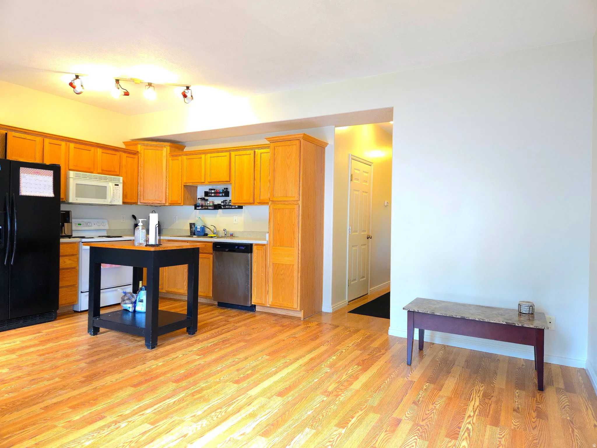 Kitchen featuring light countertops, white appliances, light wood-type flooring, and wood finish cabinets