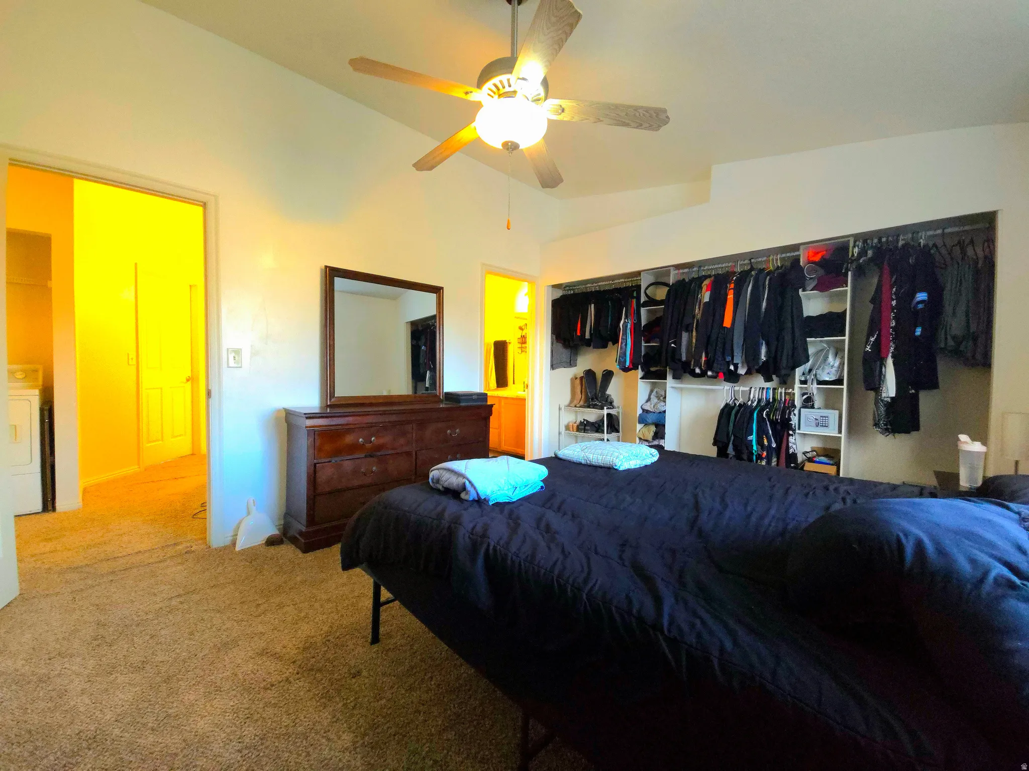 Carpeted bedroom with a closet, washer / clothes dryer, vaulted ceiling, a ceiling fan, and connected bathroom
