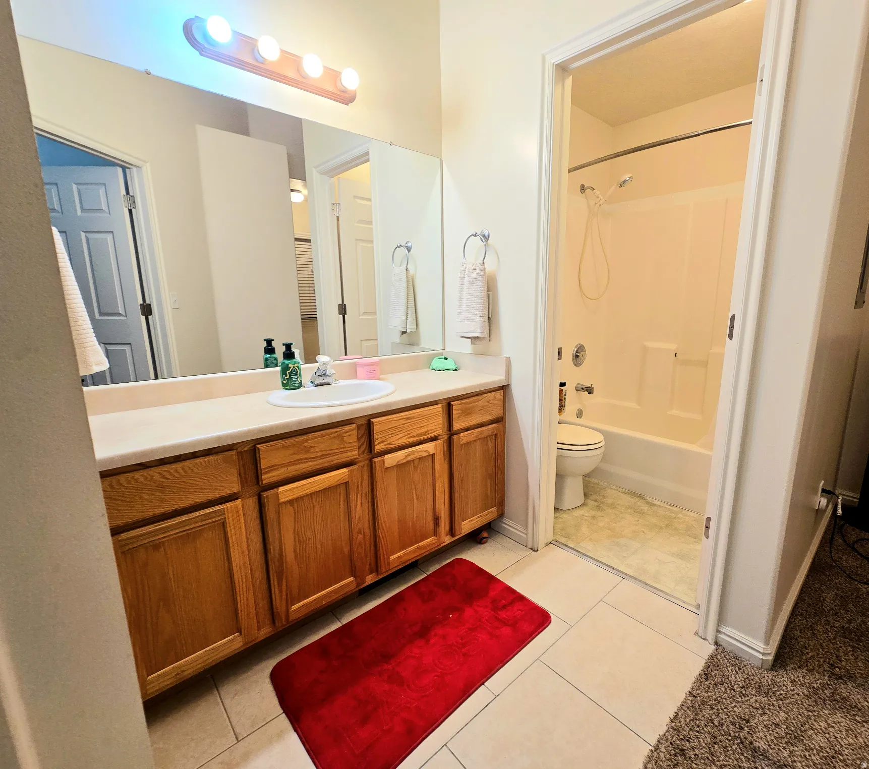 Bathroom with vanity, light tile patterned floors, and tub / shower combination