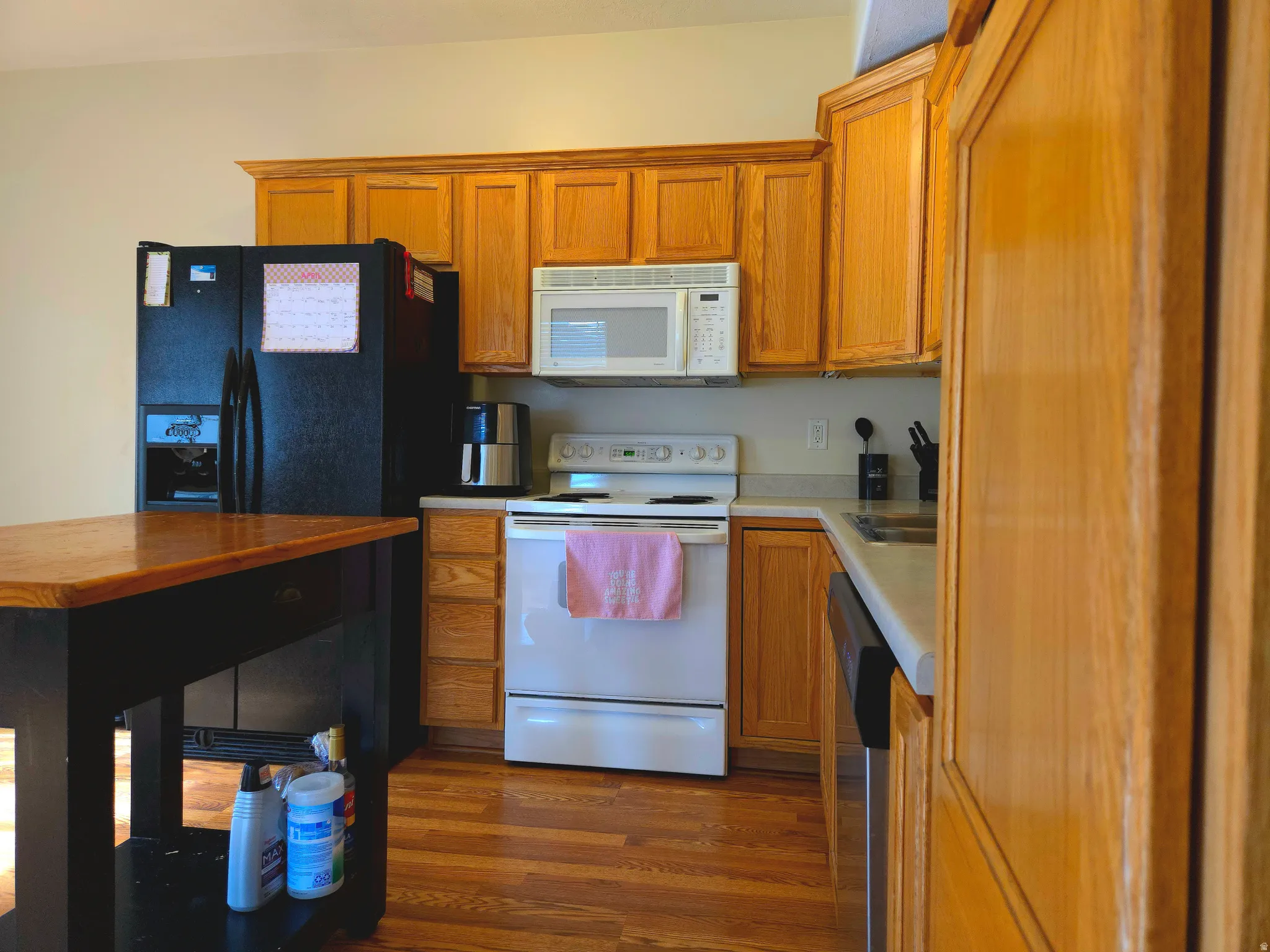 Kitchen with white appliances, wood finish cabinets, and dark wood-style floors