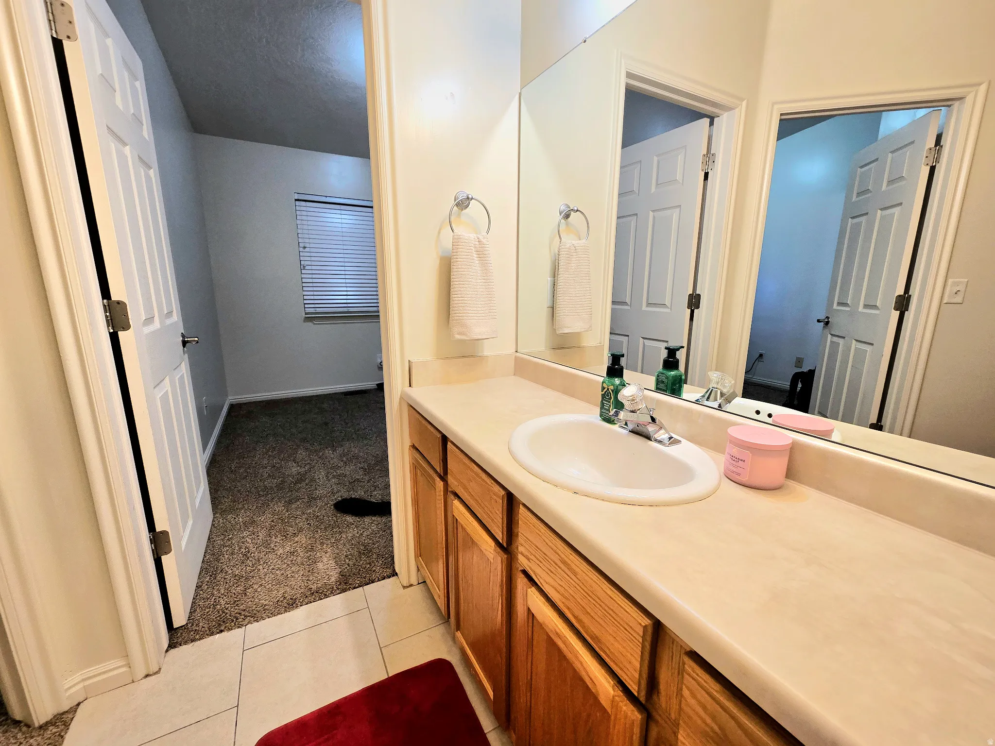 Bathroom featuring light colored carpet, vanity, and light tile patterned flooring