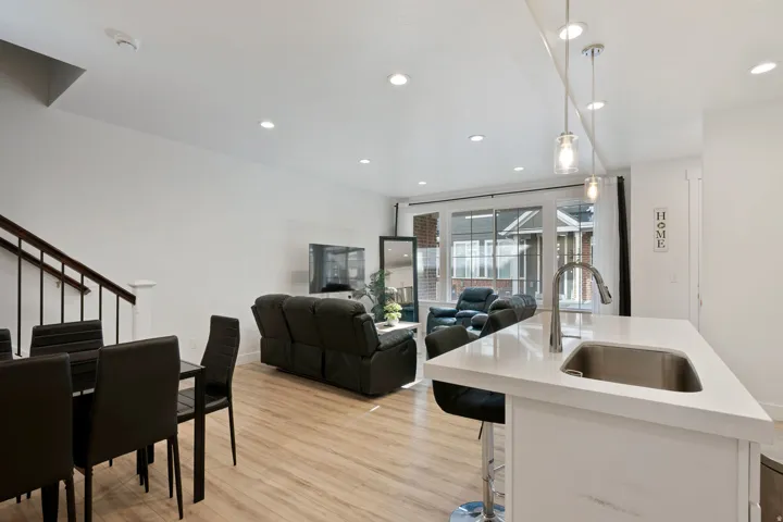 Kitchen featuring light wood-type flooring, an island with sink, pendant lighting, light stone countertops, and open floor plan