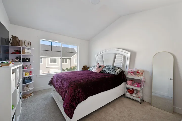 Bedroom with vaulted ceiling and light colored carpet