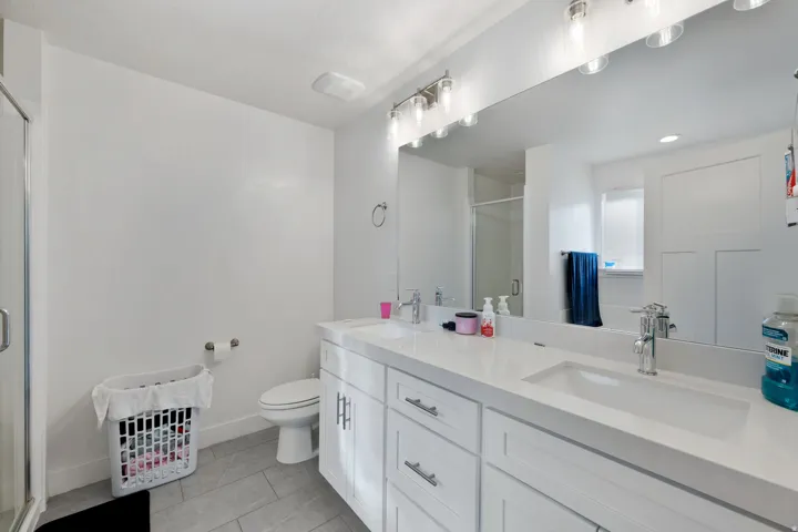 Bathroom featuring a stall shower, double vanity, light tile patterned flooring, and recessed lighting