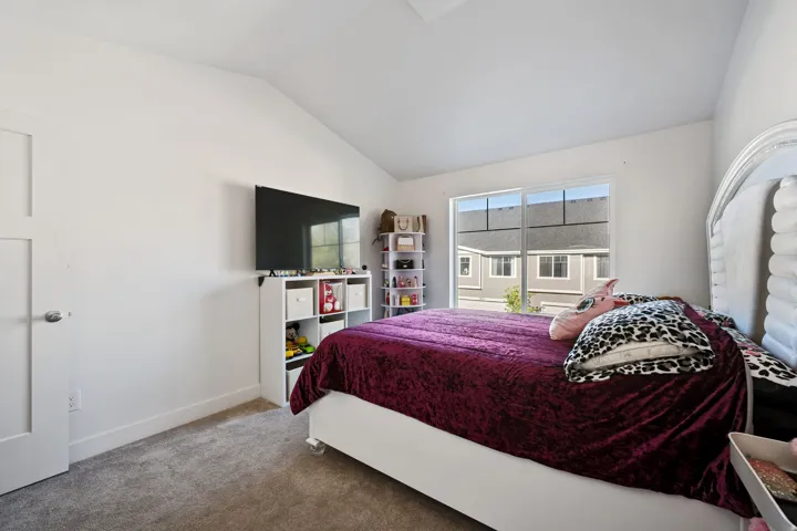 Carpeted bedroom featuring vaulted ceiling and baseboards