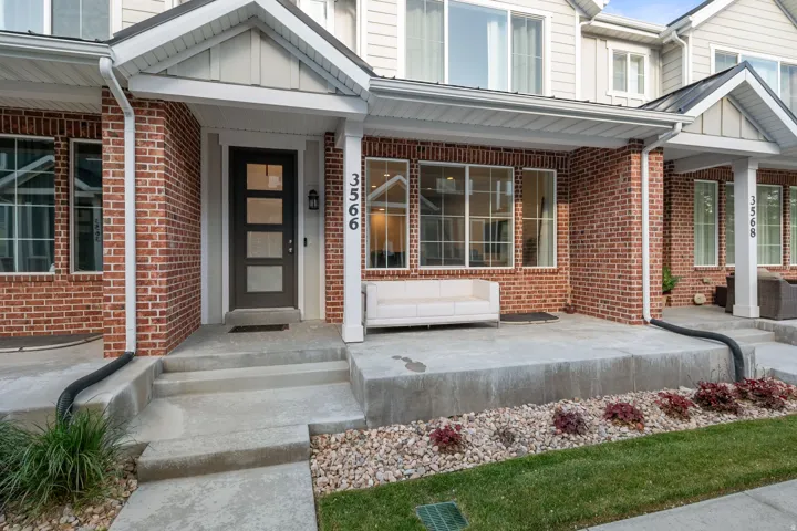 Entrance to property with brick siding, a porch, and board and batten siding