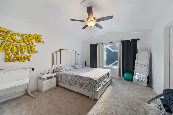Bedroom featuring lofted ceiling, light colored carpet, and a ceiling fan