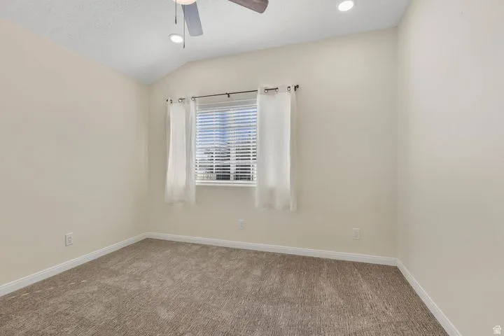 Empty room with vaulted ceiling, carpet, ceiling fan, and recessed lighting