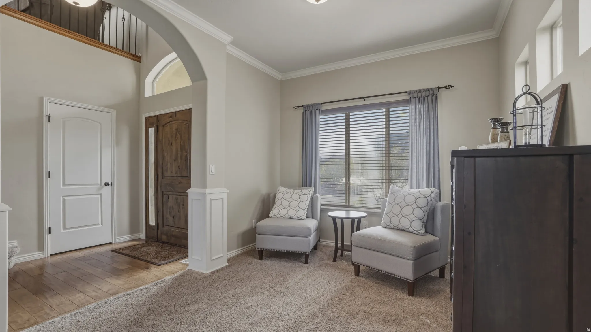 Sitting room featuring crown molding, healthy amount of natural light, light carpet, arched walkways, and light wood-style floors