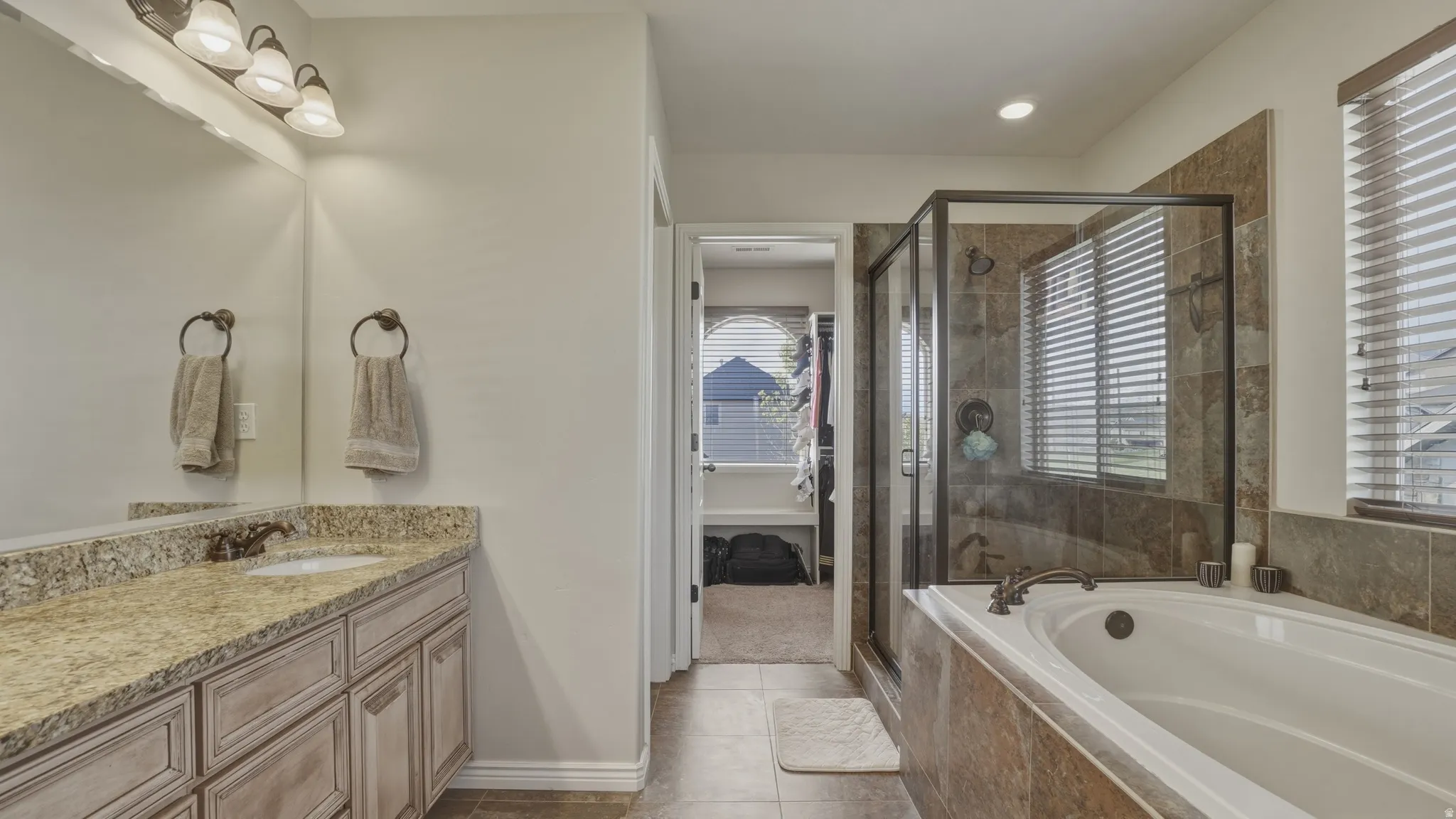 Bathroom with vanity, a stall shower, a garden tub, light tile patterned flooring, and recessed lighting