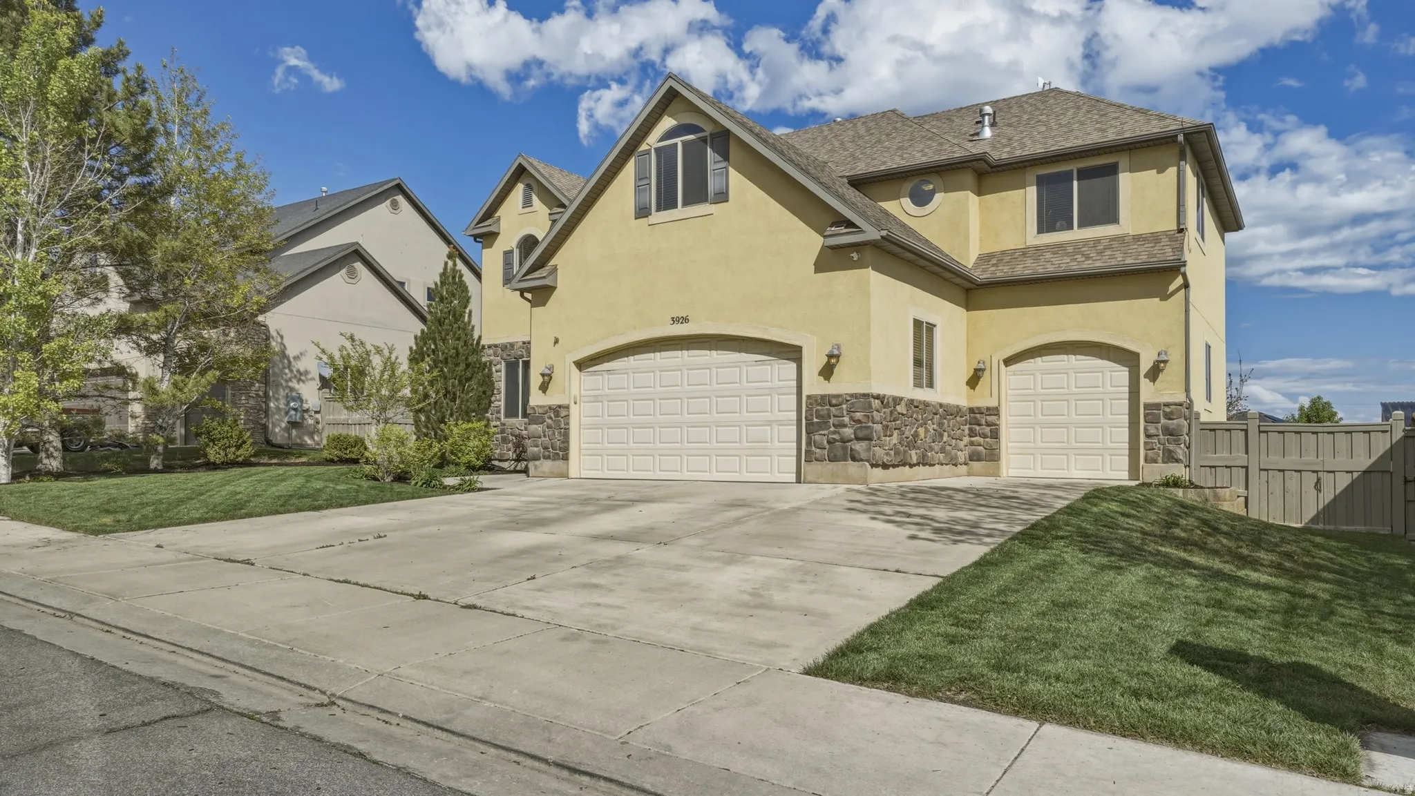 View of front of house featuring stucco siding, a garage, driveway, stone siding, and roof with shingles