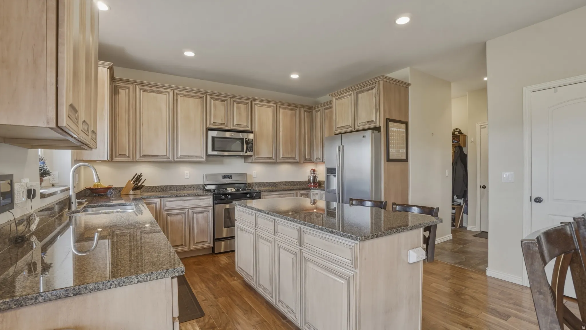 Kitchen featuring dark stone countertops, stainless steel appliances, dark wood-type flooring, a center island, and recessed lighting