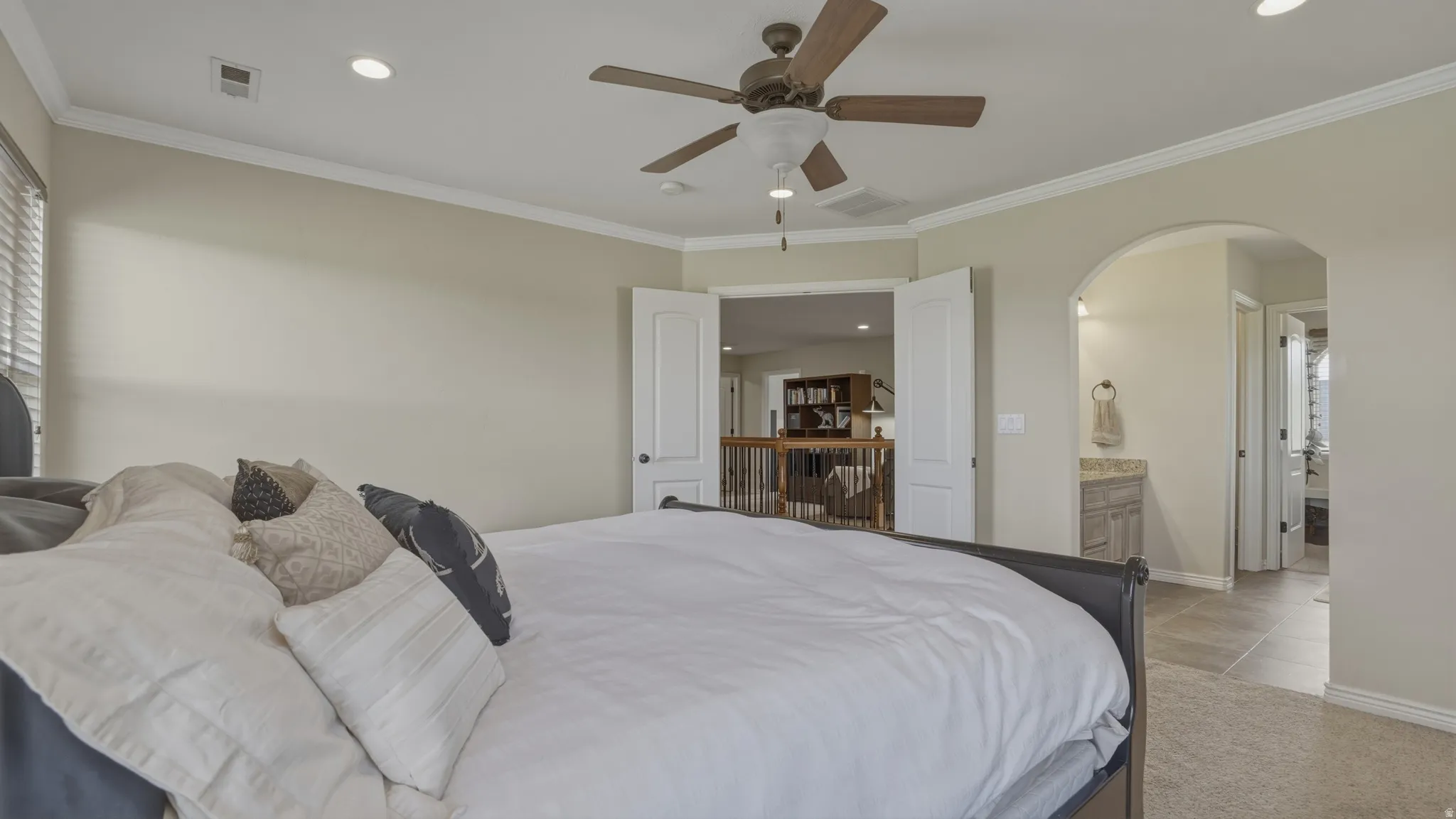 Bedroom featuring ornamental molding, arched walkways, a ceiling fan, light colored carpet, and recessed lighting