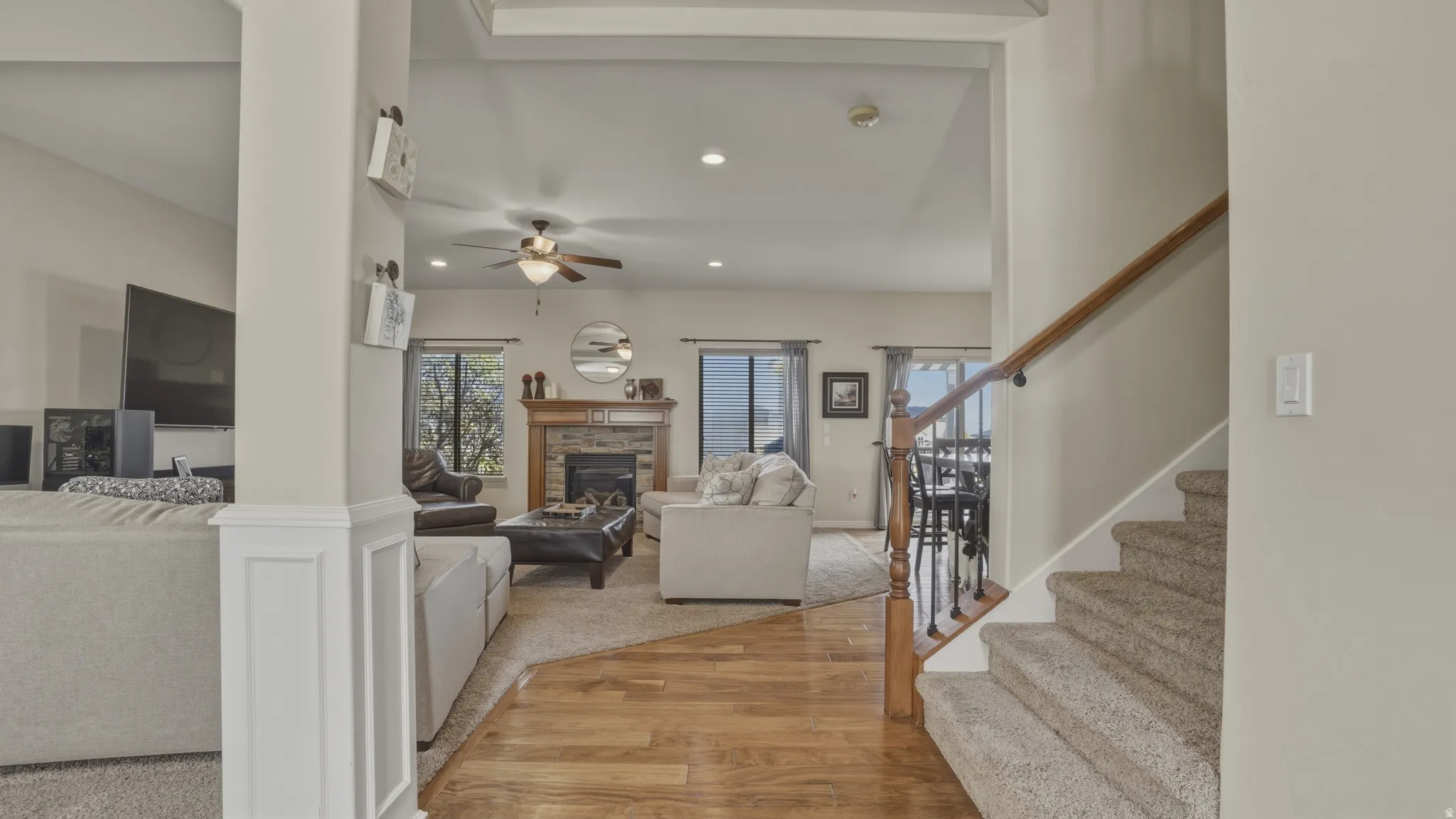 Living area with light wood-style flooring, a glass covered fireplace, recessed lighting, and a ceiling fan