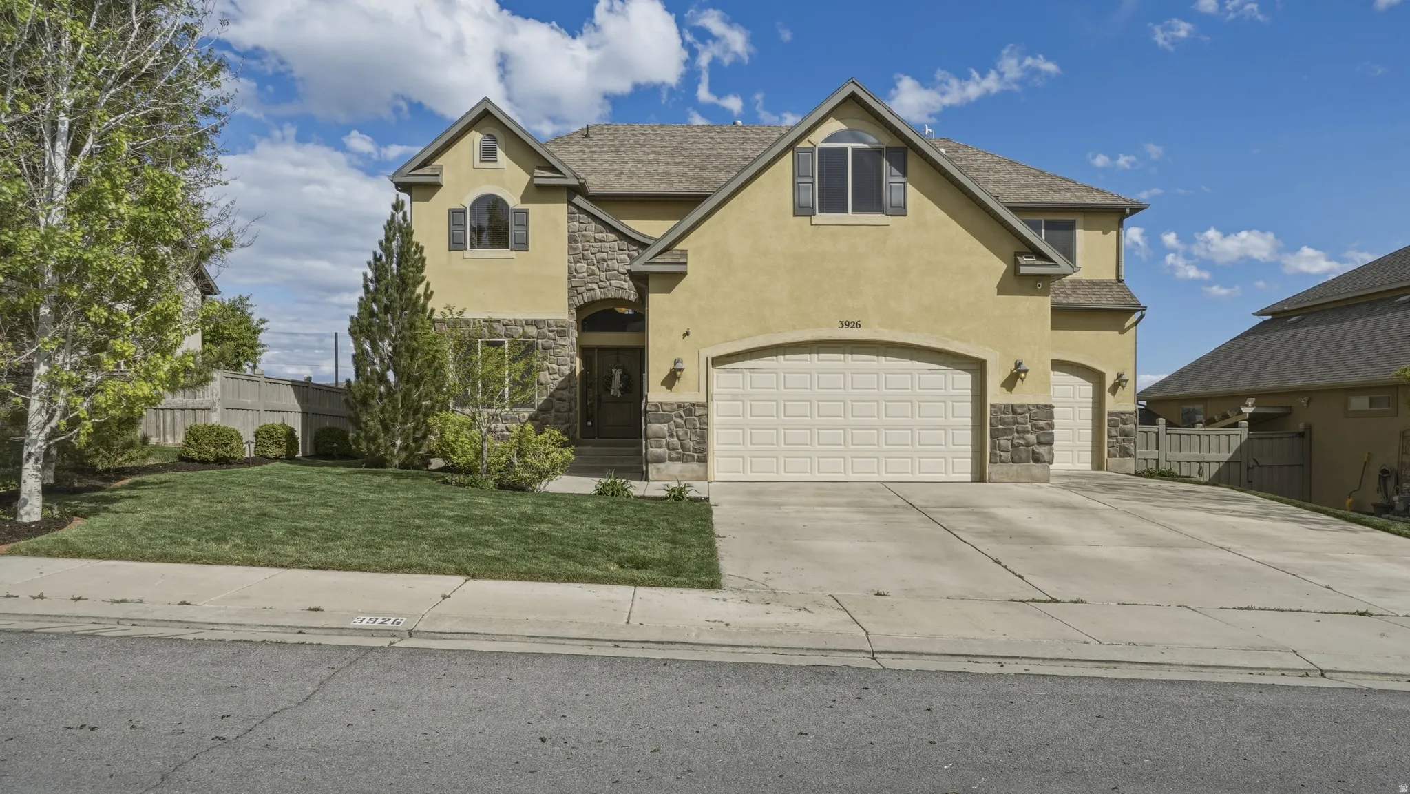 View of front of property featuring stone siding, stucco siding, driveway, and a garage