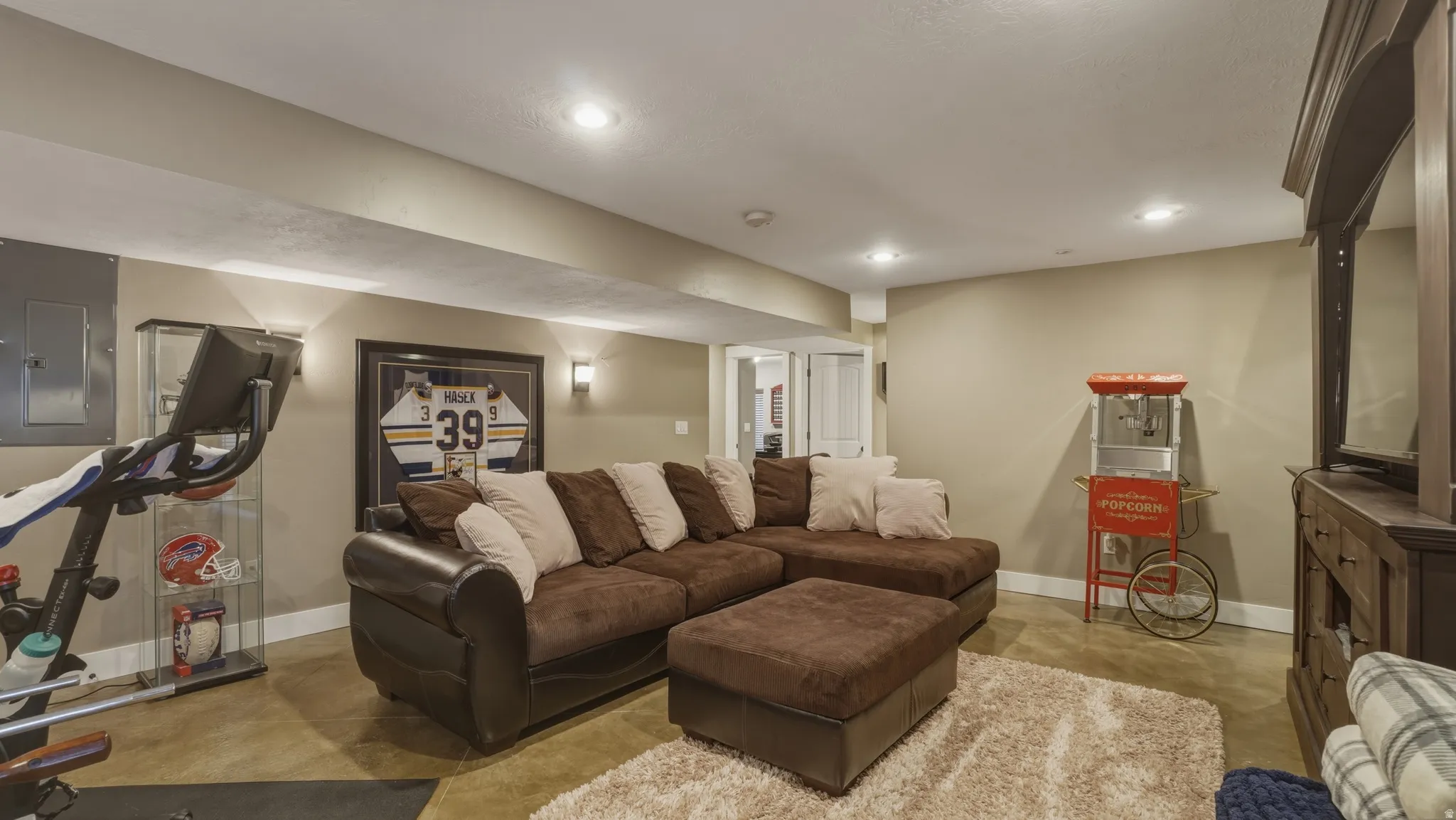 Living area with concrete floors, electric panel, and recessed lighting