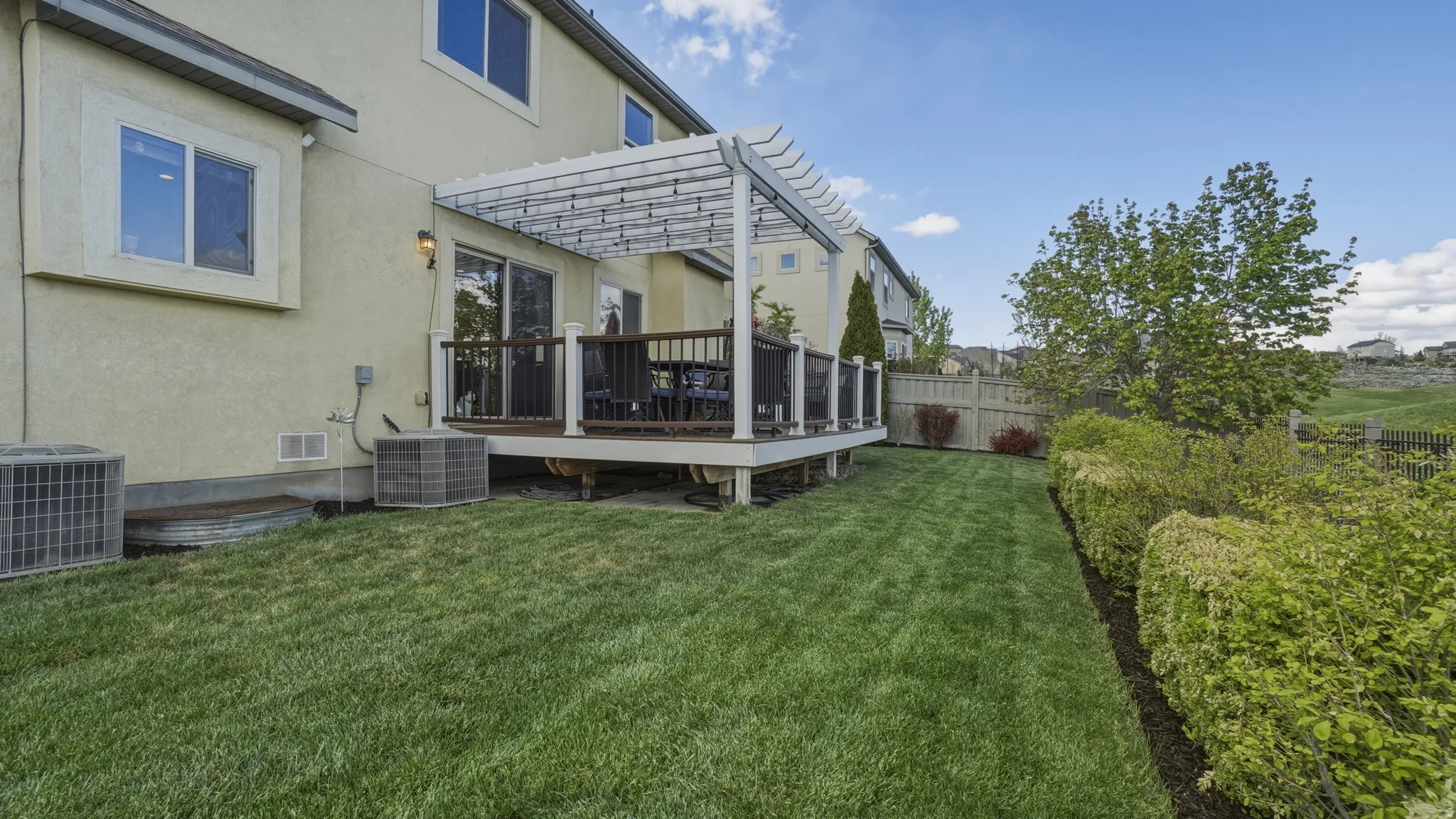 Fenced yard with a wooden deck and a pergola