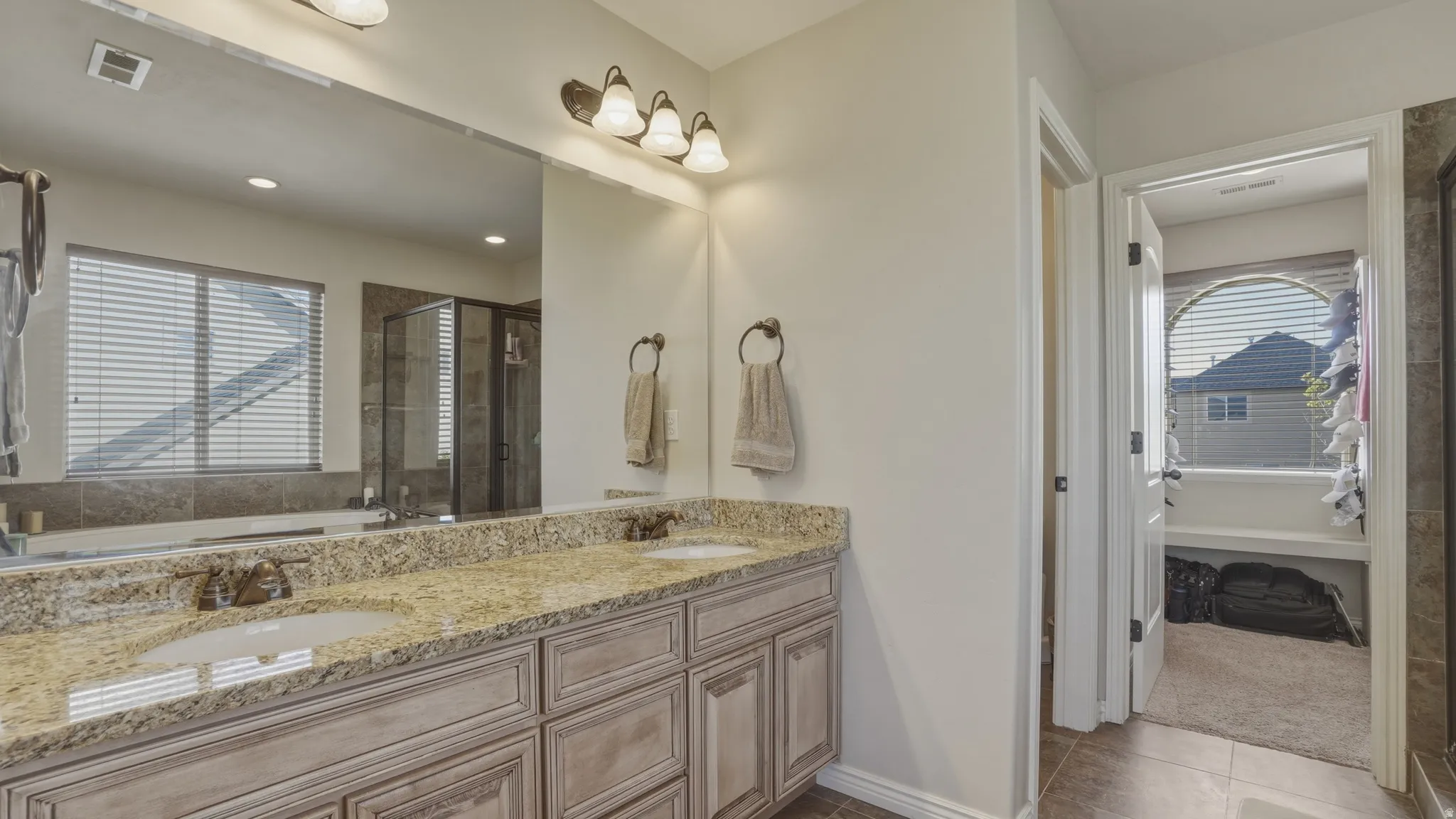 Bathroom featuring double vanity, a garden tub, a stall shower, and healthy amount of natural light