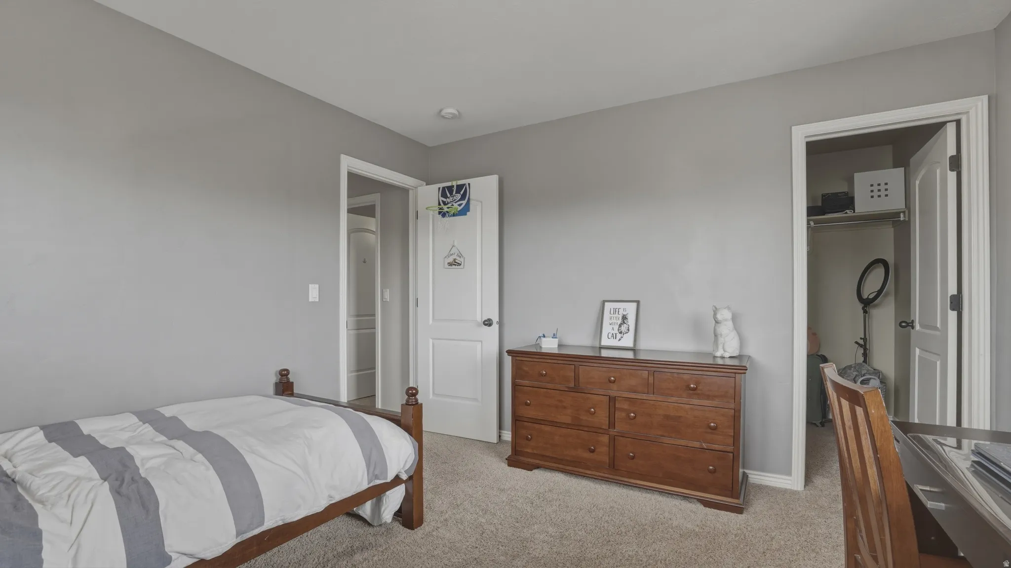 Bedroom with light carpet and a walk in closet