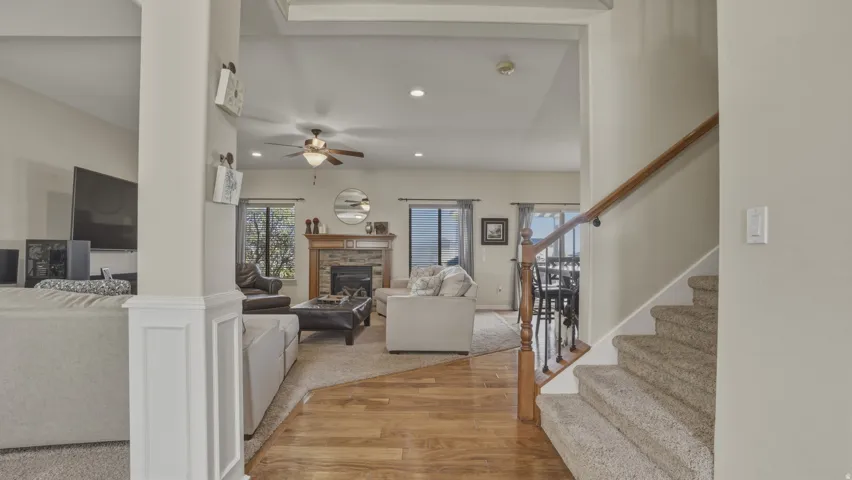 Living area with light wood-style flooring, a glass covered fireplace, recessed lighting, and a ceiling fan