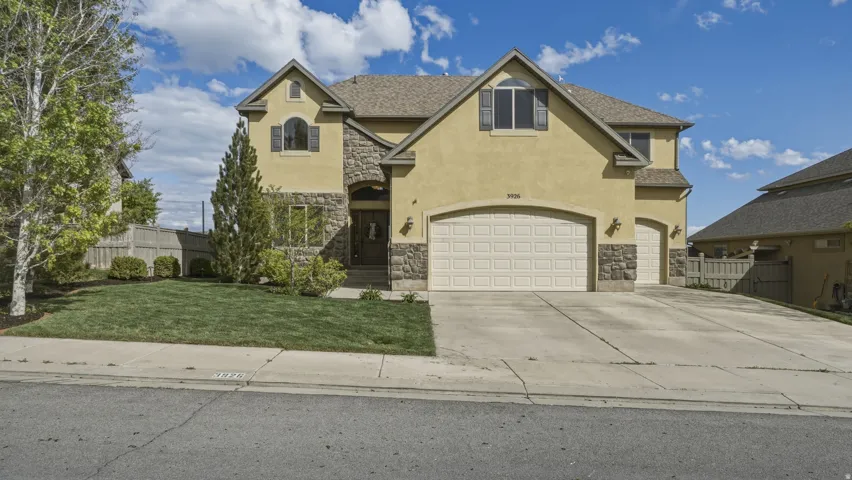 View of front of property featuring stone siding, stucco siding, driveway, and a garage