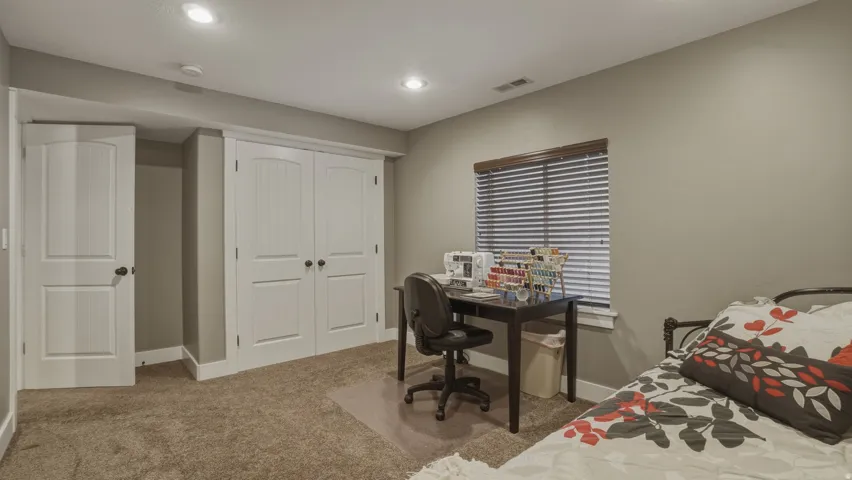 Carpeted bedroom with a closet, an office area, and recessed lighting