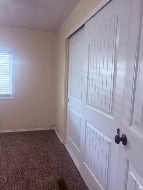 Spare room featuring dark colored carpet and baseboards