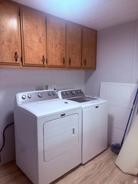 Laundry area with light wood-style floors, cabinet space, and separate washer and dryer