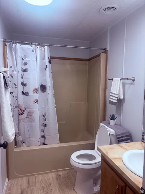 Full bathroom featuring vanity, shower / bath combination with curtain, and light wood-type flooring
