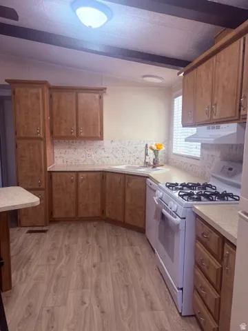 Kitchen featuring white appliances, light countertops, light wood finished floors, and wood finish cabinets