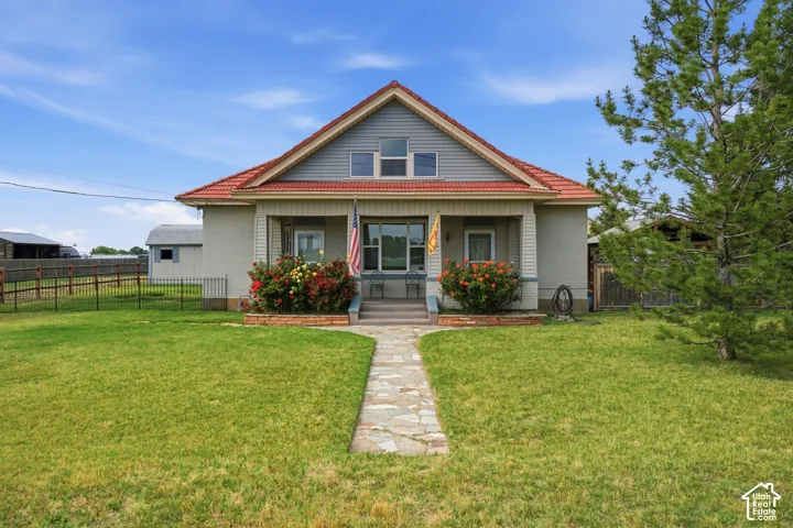 Charming exterior featuring a stone walkway, covered porch, red tile roof, and gabled dormer