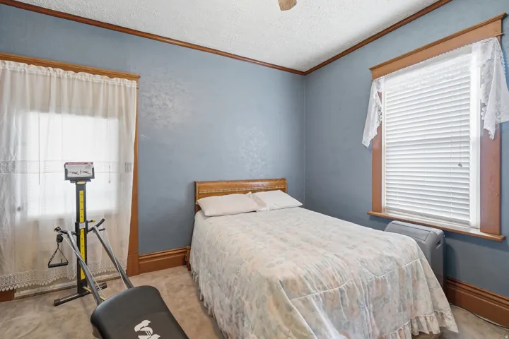 Carpeted room featuring two windows with wood trim, crown molding, and textured blue wall finishes