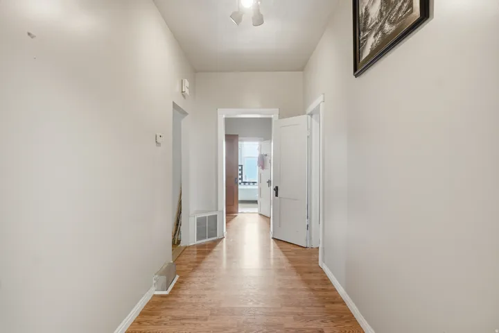 Hallway featuring wood-finish flooring, light neutral wall paint, and white trim