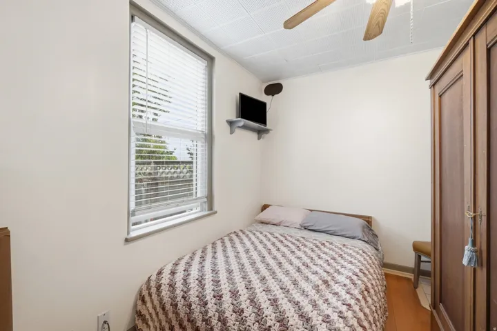 White walls, a ceiling fan, and wood-finish flooring characterize this room