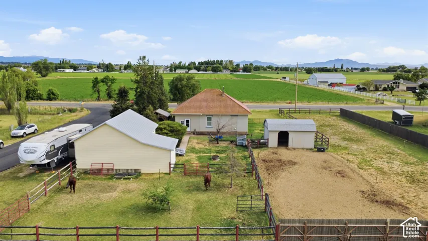 Property featuring a main residence with a prominent gabled roof, a large detached auxiliary building, fenced pasture areas, an additional outbuilding, and expansive surrounding agricultural fields