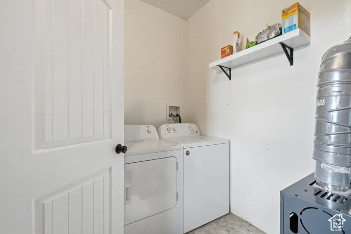 Dedicated utility area featuring a white paneled door with black hardware, neutral wall paint, and a floating wall shelf