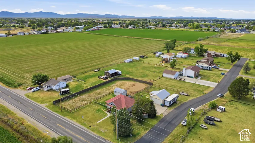 Aerial perspective showcasing multiple residential properties, expansive green fields, and a distant mountain range