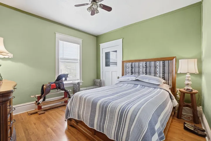 Bedroom featuring wood-finish flooring, a ceiling fan, and a single window with blinds
