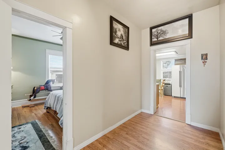 Hallway featuring wood-finish flooring, light neutral wall paint, and white trim