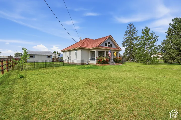 Expansive green lawn surrounds this property, featuring a light-colored exterior with a red tile roof