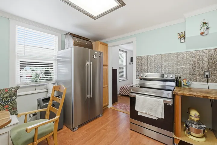 Kitchen featuring wood-finish flooring, stainless steel appliances, a pressed tin backsplash, and recessed ceiling lighting
