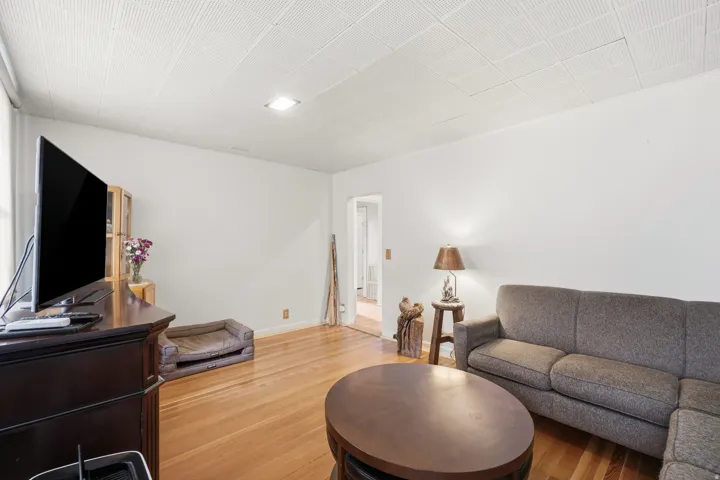 Living area featuring wood-finish flooring, white walls, and a recessed ceiling light fixture