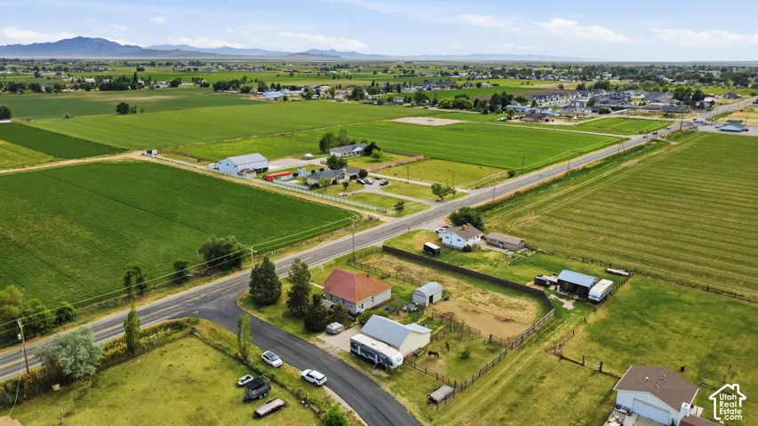 Expansive rural landscape featuring agricultural fields and scattered residential properties, bordered by paved roads