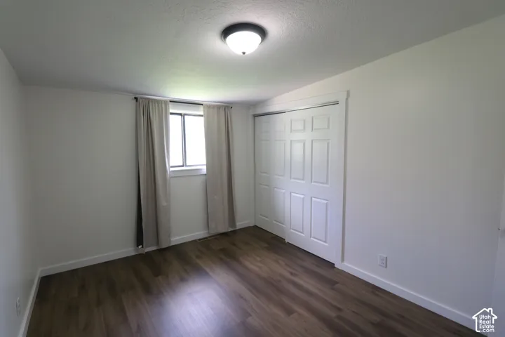 Unfurnished bedroom with a closet and dark wood-type flooring
