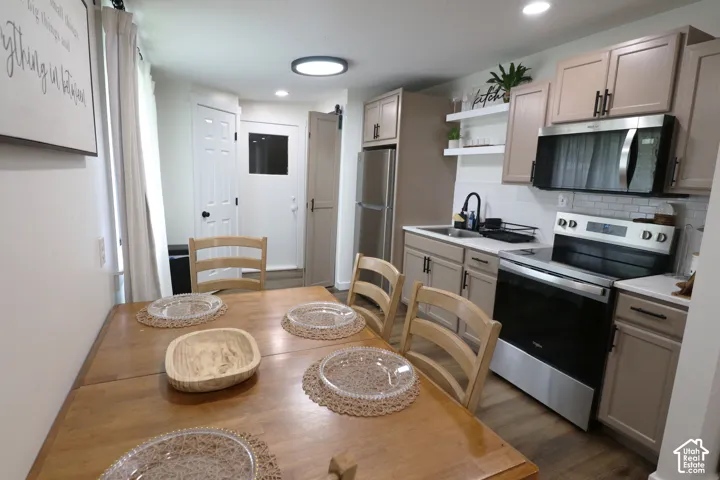 Kitchen with stainless steel appliances, light countertops, open shelves, backsplash, and recessed lighting
