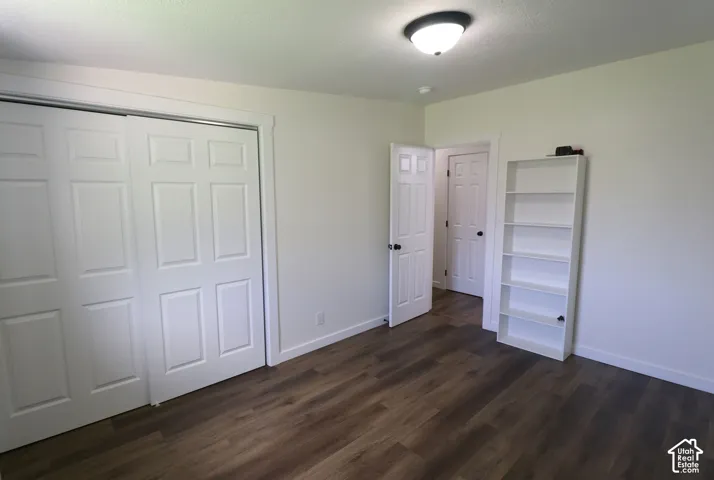 Unfurnished bedroom featuring a closet, dark wood-style flooring, and a textured ceiling