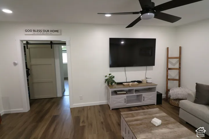 Living area featuring a barn door, dark wood-type flooring, a ceiling fan, and recessed lighting