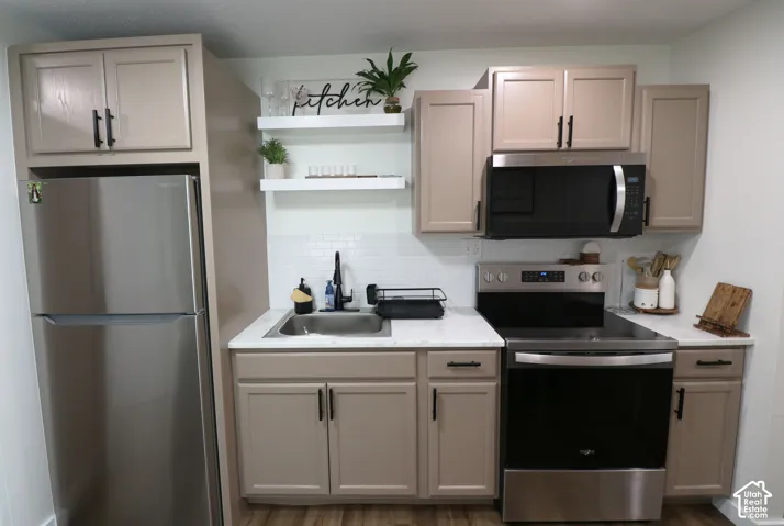 Kitchen with stainless steel appliances, open shelves, backsplash, dark wood-style flooring, and light stone countertops